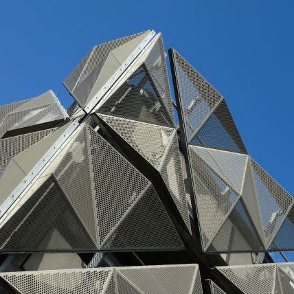 Futuristisch gebouw met geometrische, gevouwen geperforeerde panelen voor een unieke uitstraling.